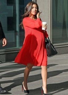 Red dress in a loose fit for pregnant women in combination with black shoes and a black bag